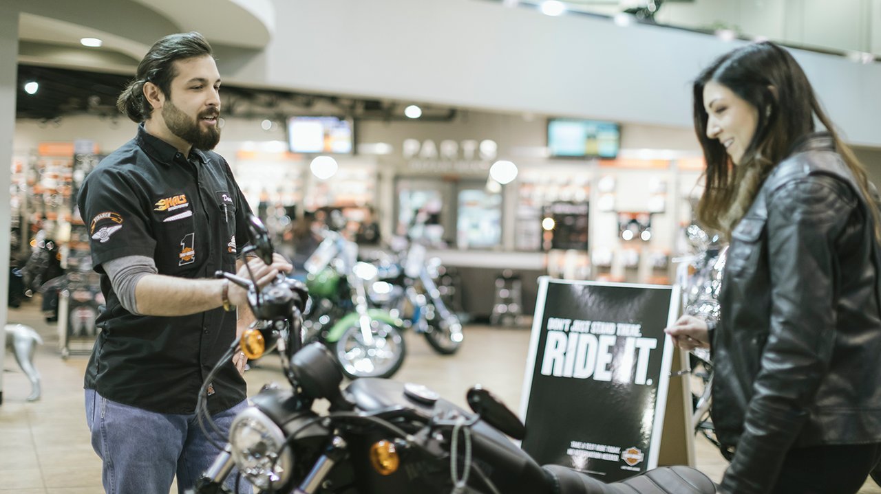 empleado del concesionario ayudando a una clienta en la tienda de motocicletas